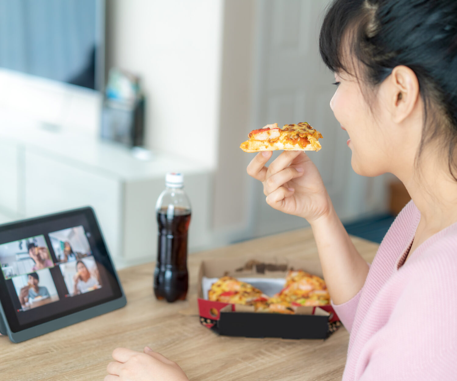 Asian woman virtual happy hour meeting party and eating food online together with her friend in video conference with digital tablet for a online meeting in video call for social distancing for infection risk.